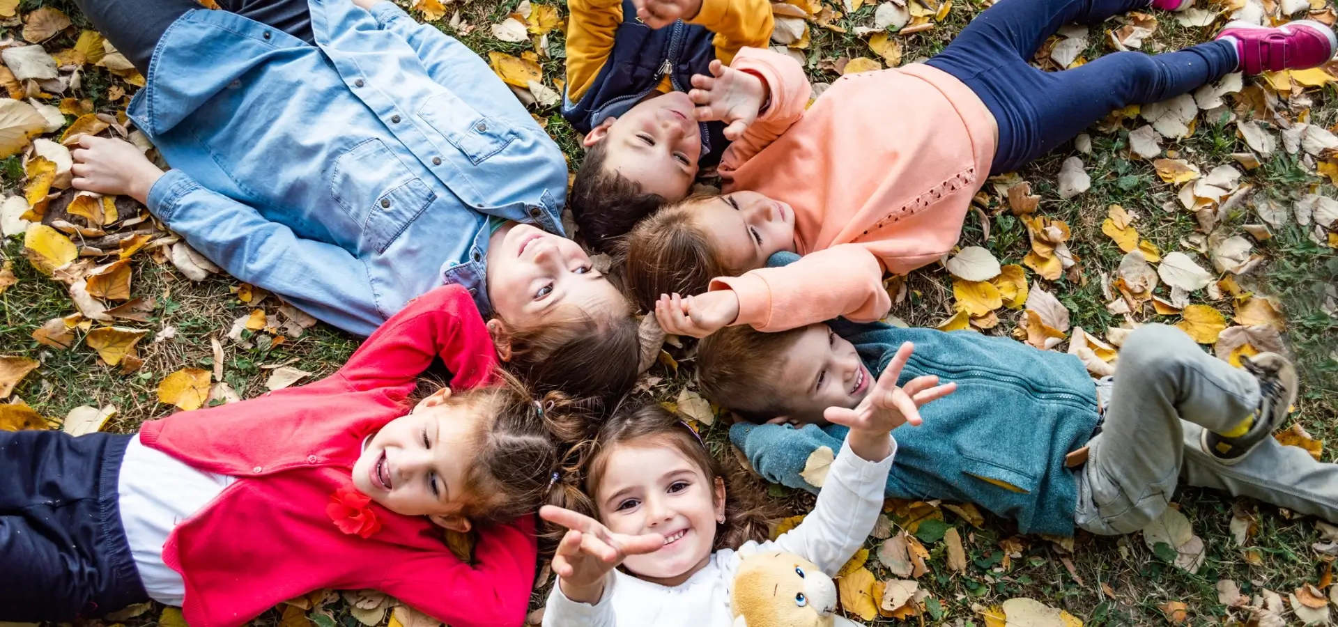 Dzieci leżące na trawie pośród liści
